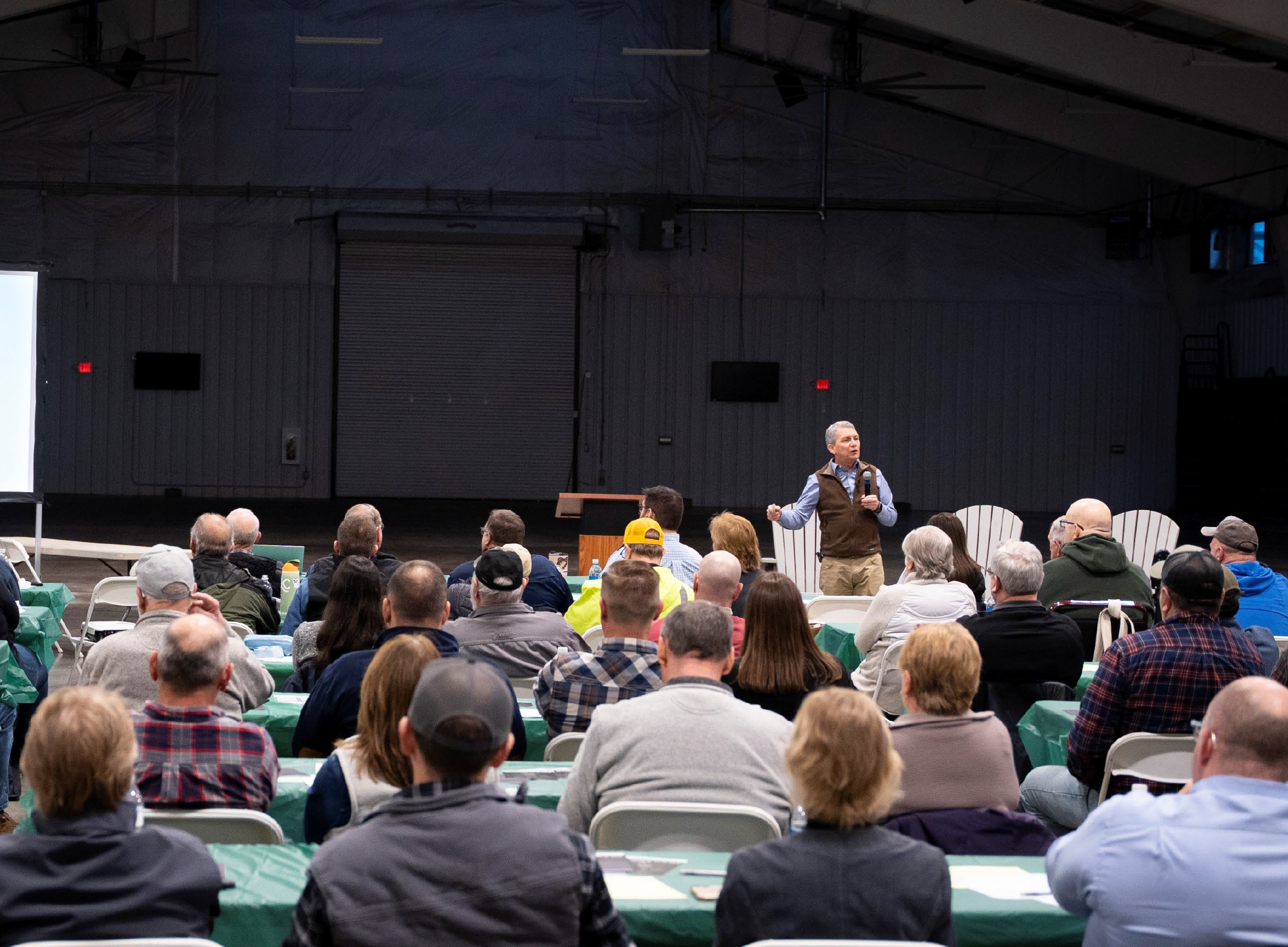 A speaker addressing a large audience during a public workshop